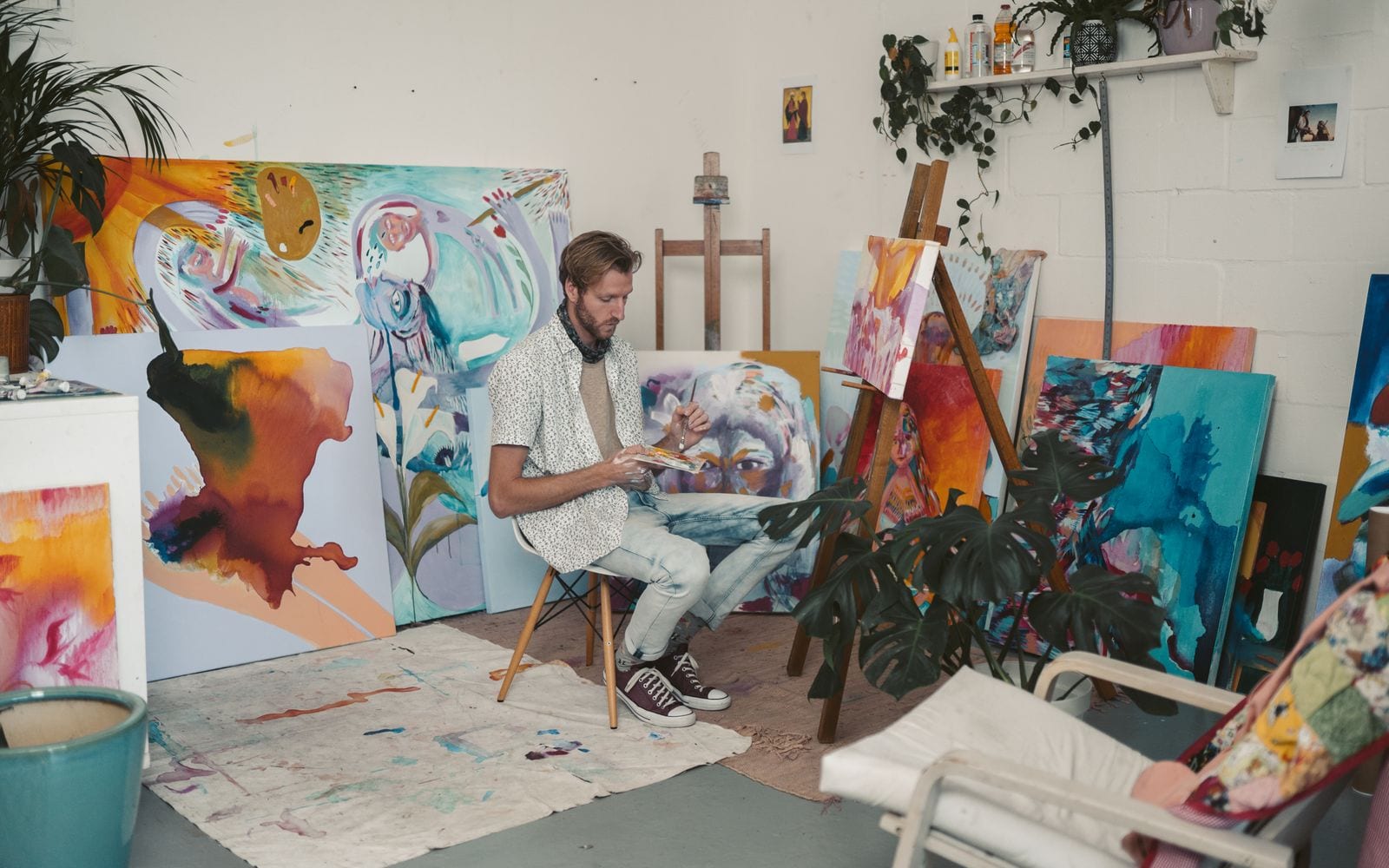 Un pittore al lavoro nel suo studio pieno di tele colorate